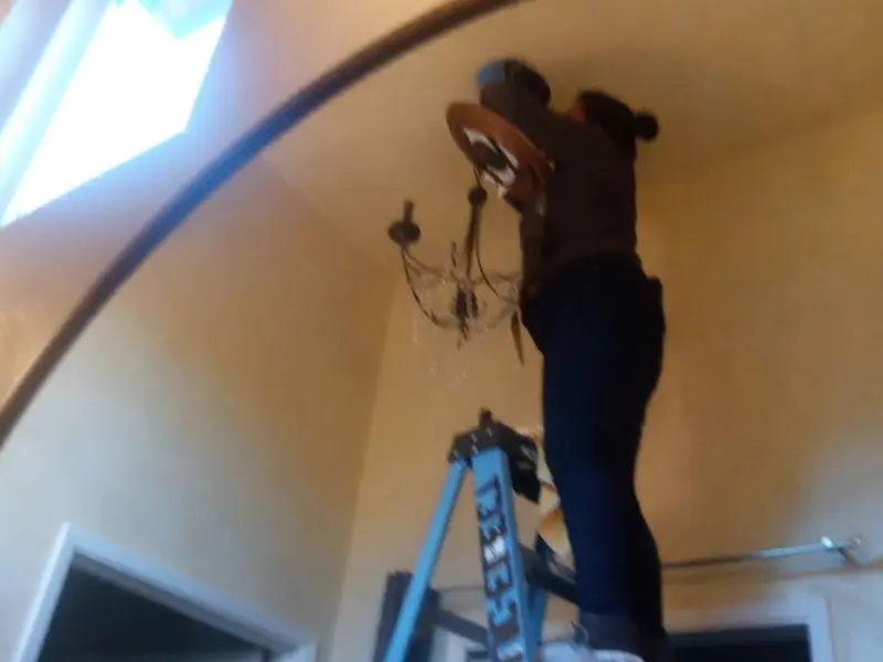 Electrician installing a chandelier in a Mussey residence